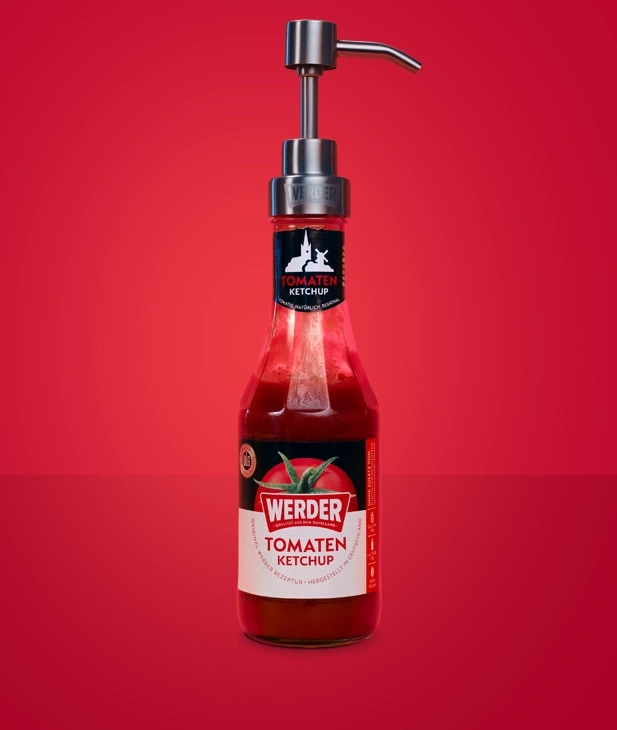 Werder Tomaten Ketchup in Glasflasche mit Pumpspender, roter Hintergrund.