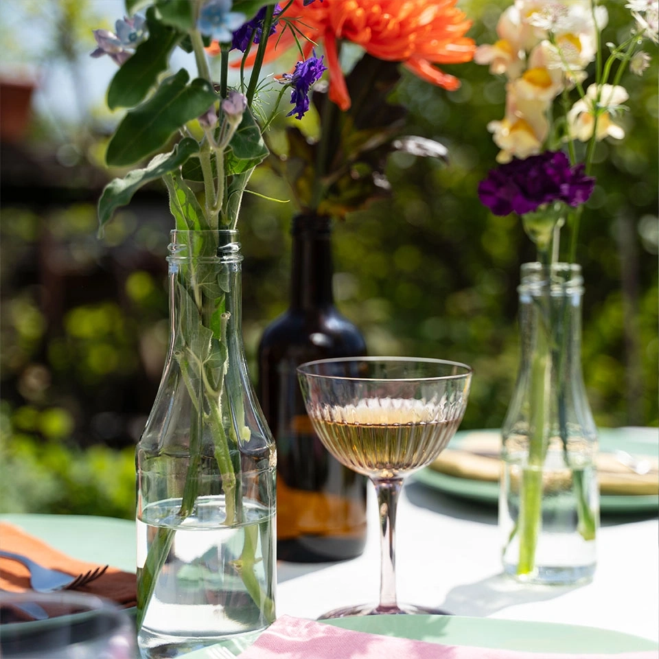Ein Tisch mit Blumen und einem Glas Wein im Freien.