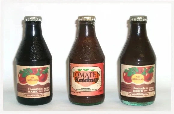 Drei Flaschen Tomaten Ketchup, eine schwarz, zwei braun, mit Etiketten.