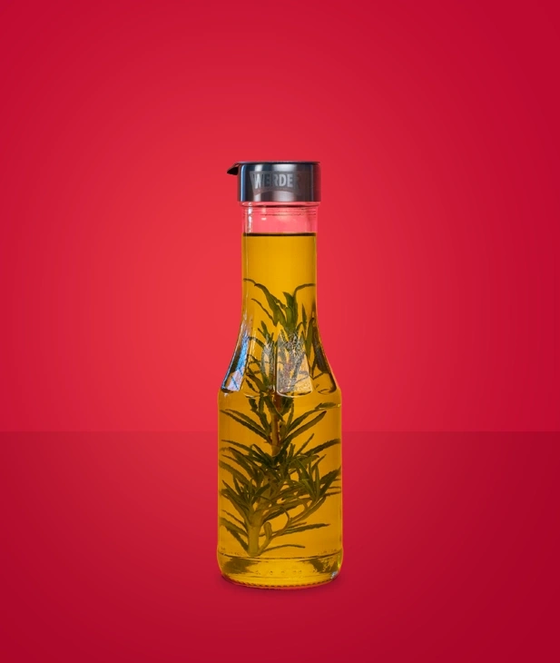 Eine Flasche Öl mit Rosmarinzweig darin.