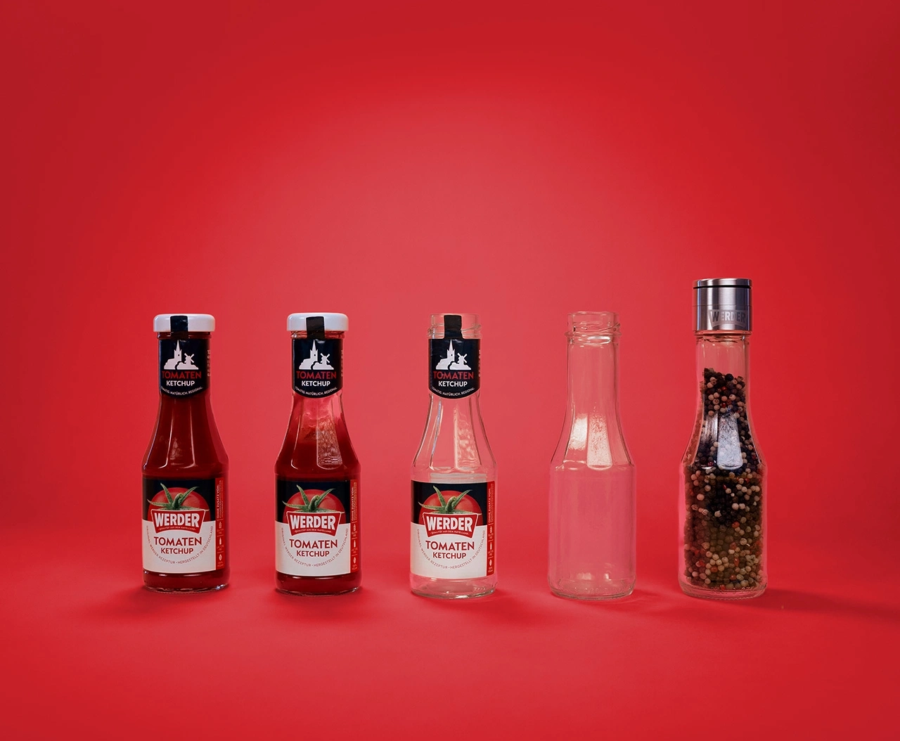 Flaschen mit Ketchup, leer und Pfeffer auf rotem Hintergrund
