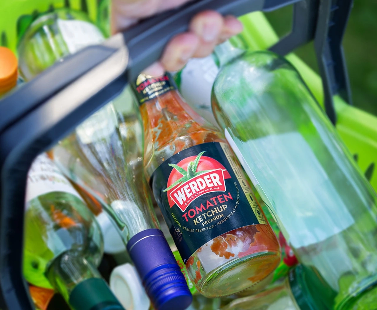 Flaschen im grünen Einkaufskorb, darunter eine Ketchup-Flasche von Werder