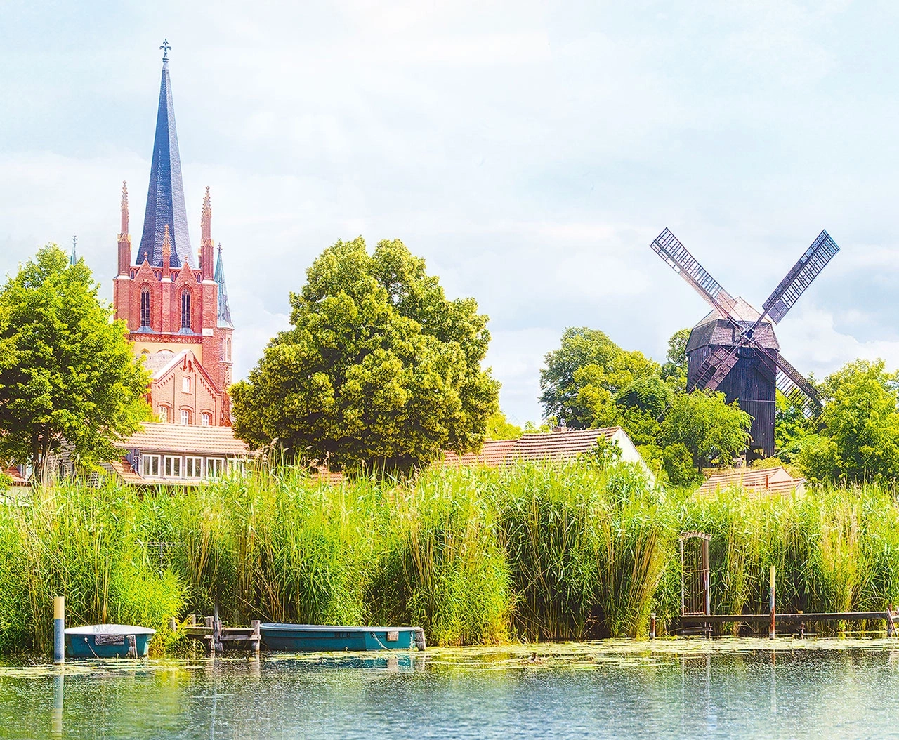 Kirche und Windmühle am Seeufer mit Booten