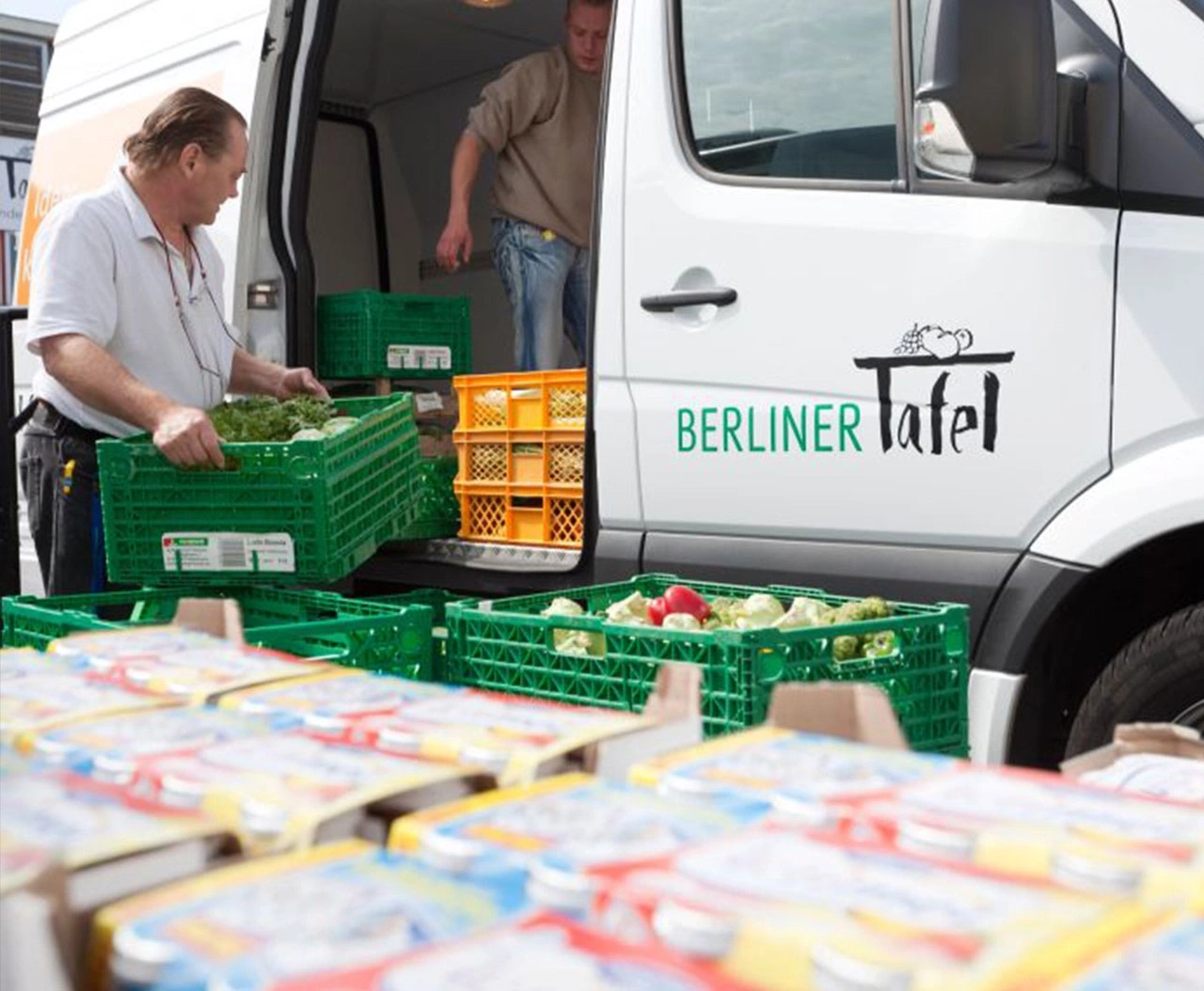 Mitarbeiter beladen einen Lieferwagen mit Lebensmittelkisten für die Berliner Tafel.